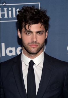 a young man in a suit and tie posing for the camera at an awards event