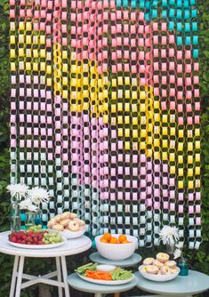 a table topped with plates of food next to a rainbow colored wall covered in grass