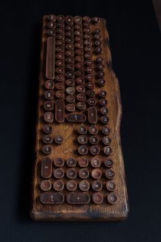 an old wooden keyboard with lots of buttons on the keys and back side, sitting on a black surface