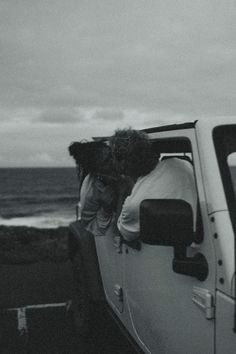 two people sitting in the back of a pick up truck looking out at the ocean