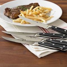 steak and french fries on a plate with knifes