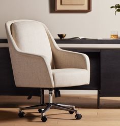 an office chair sitting on top of a hard wood floor next to a black desk