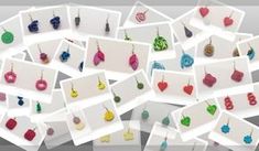 many different colored earrings hanging from hooks on white cards with black and red circles in the middle