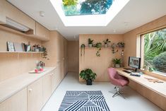 a home office with skylights and plants on the desks in front of it