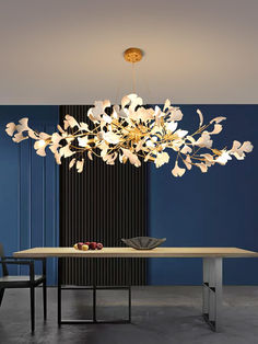 a modern chandelier hanging over a dining table in a room with blue walls