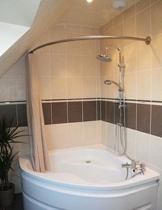 a bath tub sitting under a bathroom window next to a potted plant on the floor