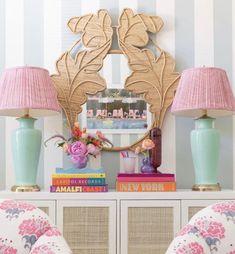 a table with two lamps and a mirror on top of it next to some books