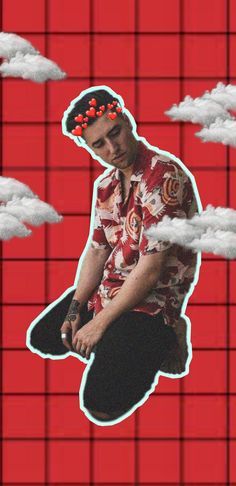 a man sitting on top of a skateboard in front of red wall with clouds