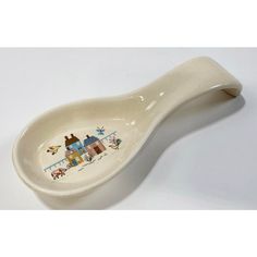 a ceramic spoon with an image of houses painted on the side, sitting on a white surface