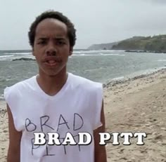 a young man standing on top of a sandy beach next to the ocean with words brad pitt