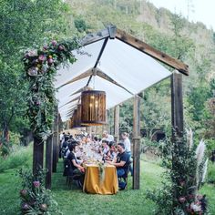 a group of people sitting at a table under a tent in the middle of a field