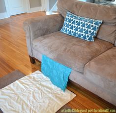 a brown couch sitting on top of a hard wood floor next to a blue and white pillow