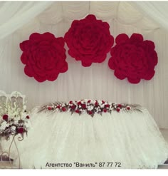 red roses are on the wall above a white table cloth and flowers in vases