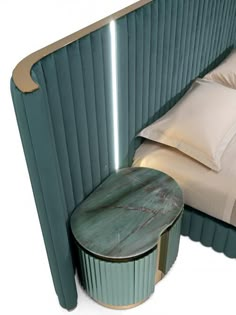 a bed with a green headboard next to a small round table and two pillows