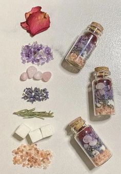 several jars filled with different types of stones and flowers next to each other on a white surface