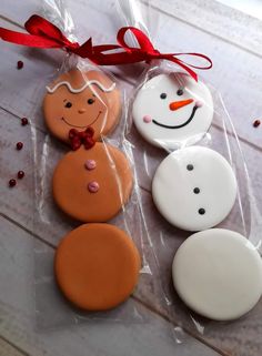 three decorated cookies sitting on top of a plastic bag next to a red bow and ribbon