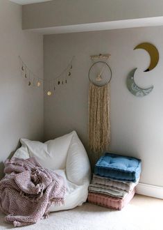 a bed with pillows and blankets on top of it in front of a wall hanging