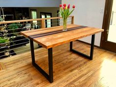 a wooden table sitting on top of a hard wood floor next to a glass vase with flowers in it