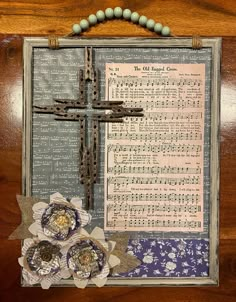 a cross and some paper flowers on a wooden table