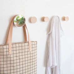 a tote bag hanging on the wall next to a coat rack with three hooks