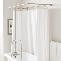 a white bath tub sitting next to a shower curtain in a bathroom on top of a hard wood floor