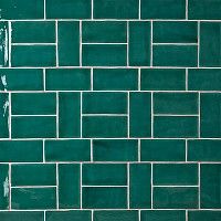 a green tiled wall with white grouting