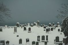 a cemetery covered in snow with lots of tombstones