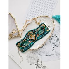 a white plate topped with a blue and green beaded purse