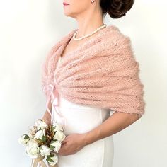 a woman in a white dress holding a bouquet of flowers and a pink shawl