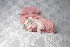 a small white dog laying on top of a bed next to a pink blanket and pillow