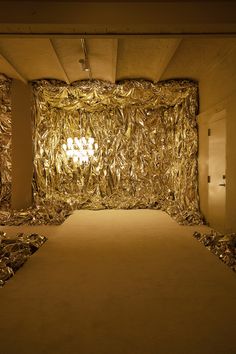 an empty room with gold foil covering the walls and carpeted floor, as well as a chandelier hanging from the ceiling