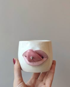 a hand holding a white cup with pink lips on it