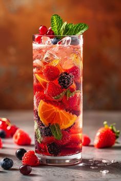 a tall glass filled with fruit and ice on top of a table next to berries