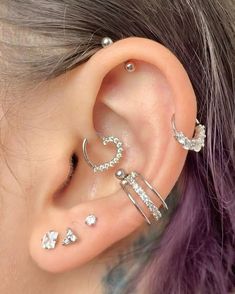 a woman with purple hair wearing three different ear piercings