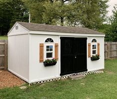 a small white shed with windows and shutters