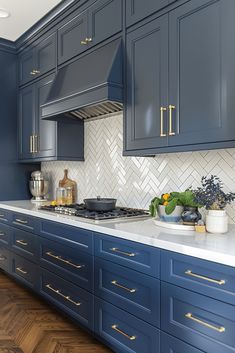 a kitchen with blue cabinets and white counter tops, gold trim on the drawers and brass pulls