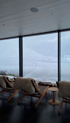 chairs and tables in front of large windows overlooking the snow covered mountains, with an ocean view