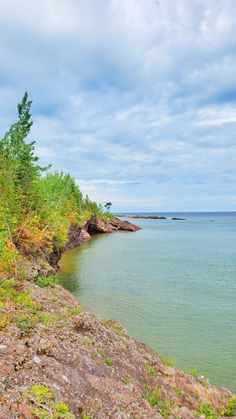 the water is calm and blue with green trees on both sides in the foreground