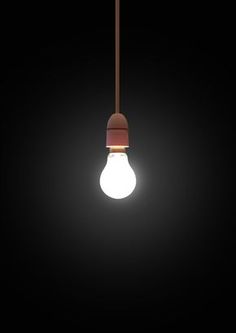 a light bulb hanging from a brown cord on a black background with the light turned on