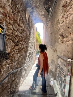 two women are walking up the stairs in an alleyway with stone walls and cobblestone flooring