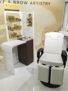 a white chair sitting in front of a display case with gold colored items on it