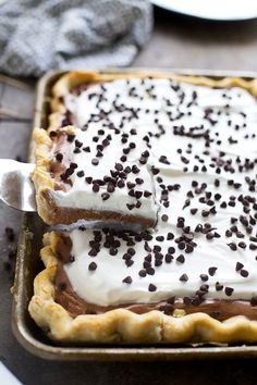 a chocolate pie with white frosting and sprinkles is on a pan