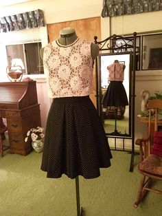 a dress on display in a room with green carpet and wooden chair next to it