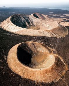 an aerial view of two large mounds in the middle of a barren area with dirt and grass