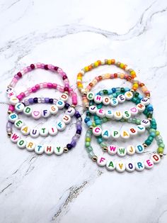 four bracelets with words on them sitting on a marble surface