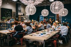 people sitting at tables in a restaurant with chandeliers hanging from the ceiling