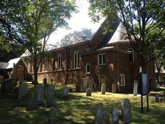 an old brick church surrounded by trees and tombstones