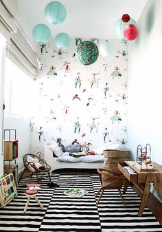 a room with a black and white striped rug, wooden furniture and wallpaper on the walls