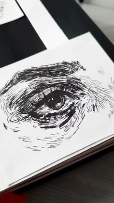 an eye is drawn on top of a piece of paper with black and white ink