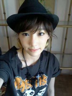 a young woman wearing a black hat and t - shirt is posing for the camera